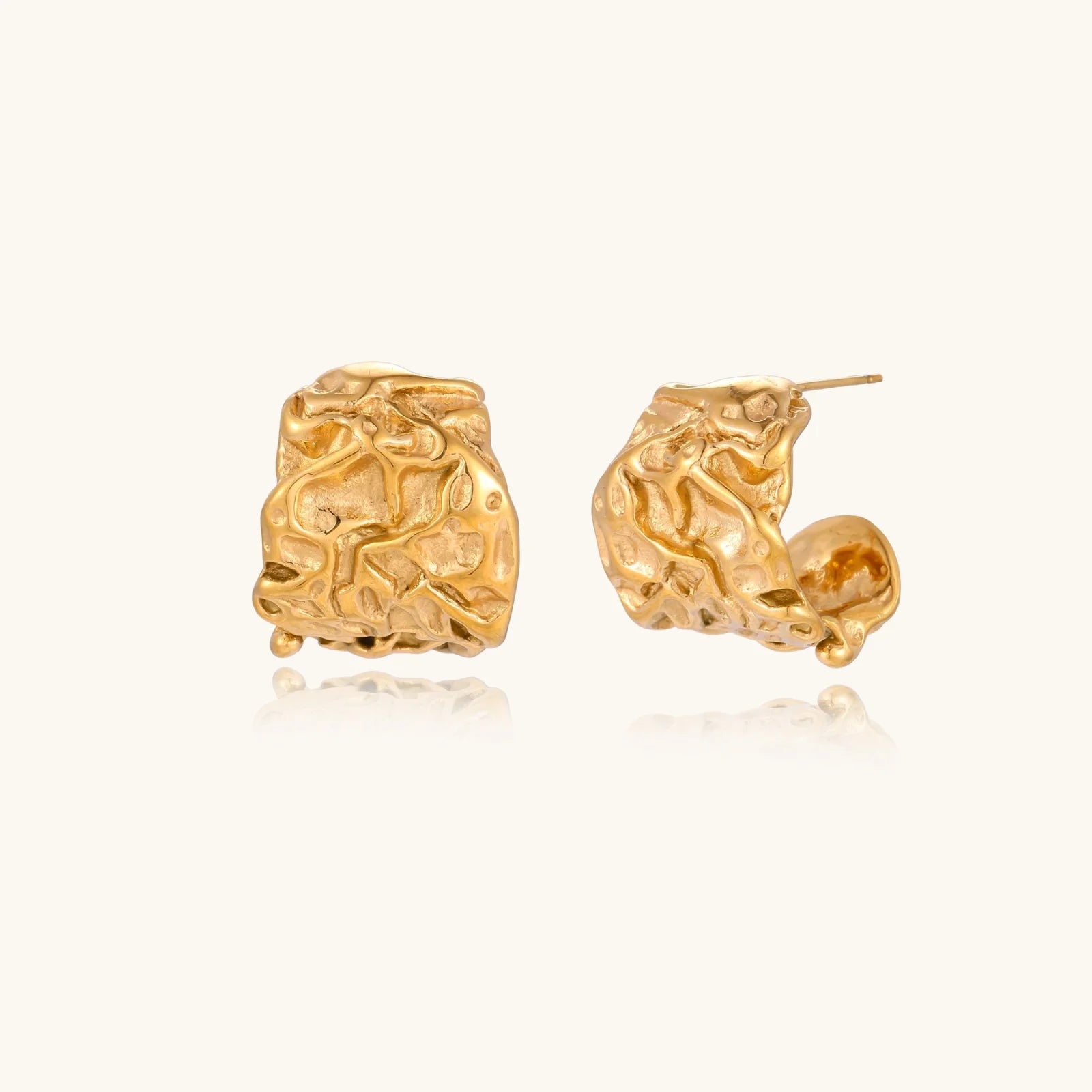 Sculptural gold-plated hoops with organic crushed texture on cream background
