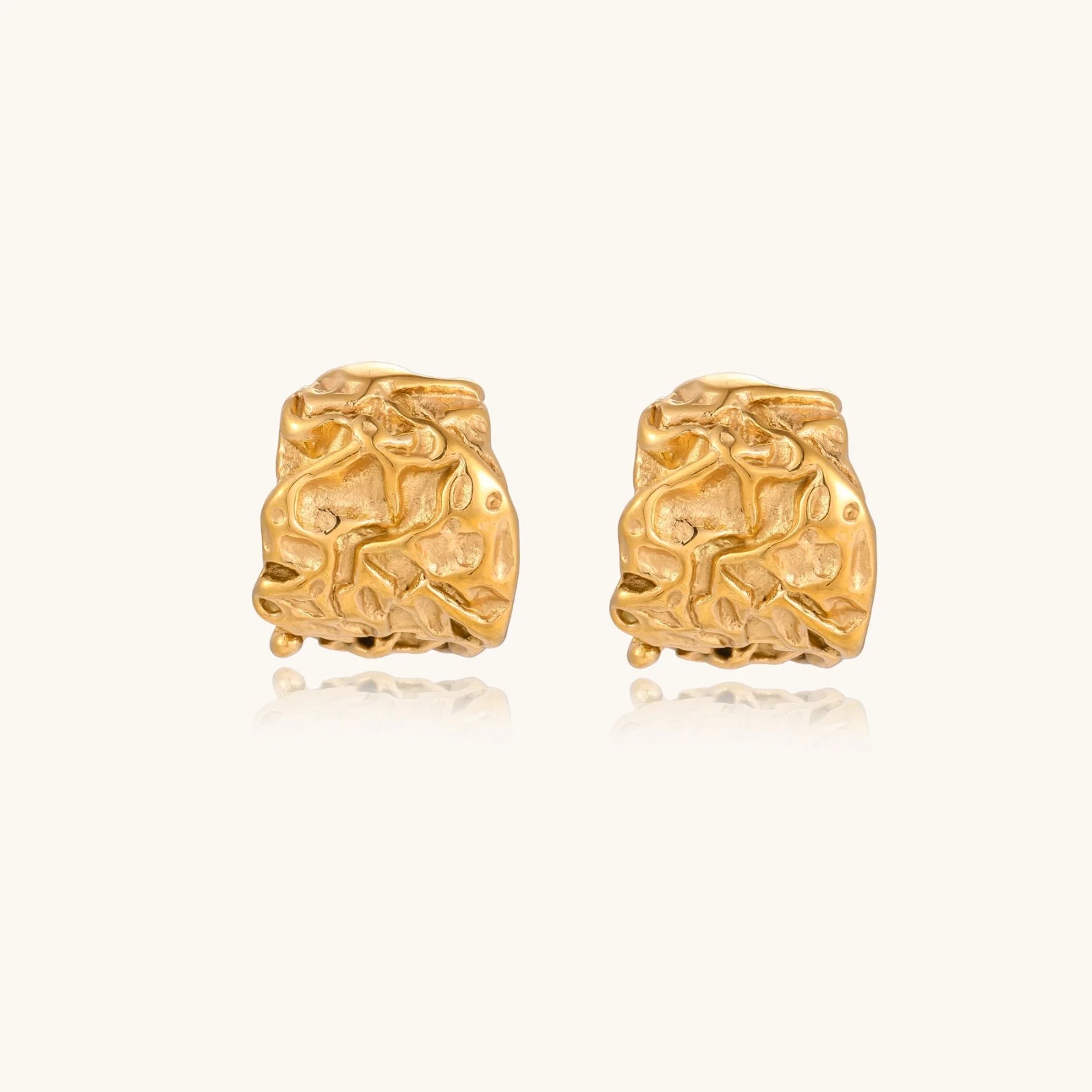 Sculptural gold-plated hoops with organic crushed texture on cream background